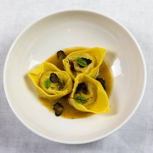 La missione di Valle di Assisi Tre tortellini con salsa e tartufo in un piatto bianco