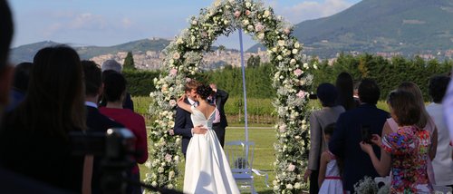 La missione di Valle di Assisi Sposi che si baciano sotto un arco di fiori durante una cerimonia all'aperto