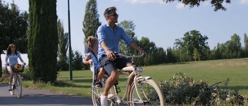 Deluxe room Man cycling with a child on the back seat in a sunny park
