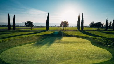Resort Hotel Assisi com Padel Tennis Bike Hotel 3 swimming pools soccer field. Golf course at sunset with trees and low sun on the horizon