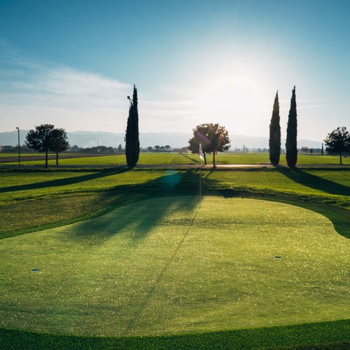 La missione di Valle di Assisi Campo da golf al tramonto con alberi e sole basso all'orizzonte